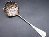 a silver spoon with a leaf shaped handle on a black surface