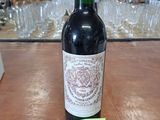 une bouteille de vin posée sur une table, avec des verres en arrière-plan