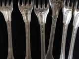 six forks are lined up in a row on a black surface