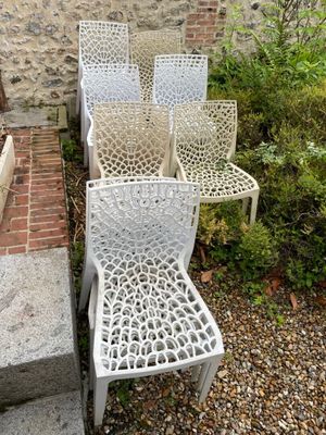 four white chairs sitting in front of a brick wall