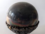 une boule métallique posée sur un socle, sur une surface blanche
