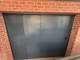 une porte de garage basculante dans un bâtiment en briques