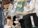 a mickey mouse stuffed animal sitting next to a pile of clothing