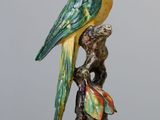 a figurine of a parrot sitting on a tree branch