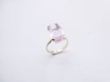 une bague en pierre rose posée sur une surface blanche