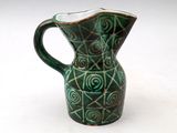 a green and white pitcher on a white surface
