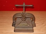 an old cast iron press sits on a wooden table