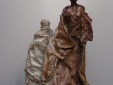 sculpture représentant une femme et un homme assis sur une estrade en bois