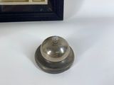 a silver bell sitting on a table next to a framed picture