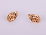 a pair of gold earrings on a white surface