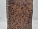 an old book with a brown cover sitting on top of a white surface
