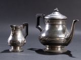 a silver tea pot and a silver cup on a table