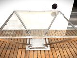 une table en verre avec un piètement en métal posée sur un parquet