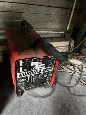 a red and black welding machine sitting in a garage