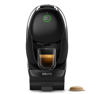 Une machine à café Krups avec une tasse de café à côté