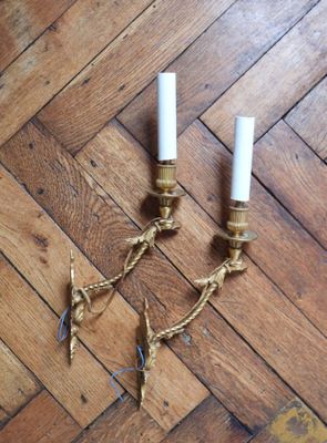 two candles are sitting on a wooden floor with rope wrapped around them