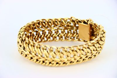 a close up of a gold bracelet on a white surface