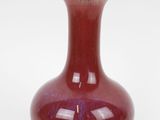 a red vase that is sitting on a white surface