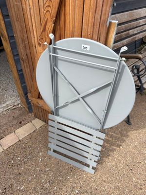 a metal chair that is sitting next to a wooden fence