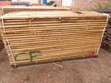 a pile of wooden planks stacked on top of each other in front of a building