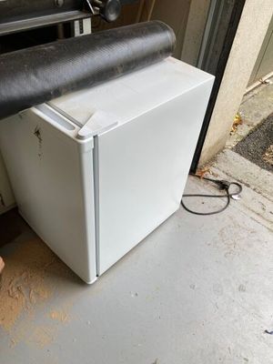 un réfrigérateur blanc posé devant la porte d'un garage
