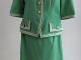 un tailleur-jupe vert sur un mannequin, devant un fond blanc