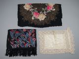 three pieces of cloth with flowers and fringes are on a table
