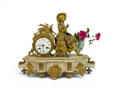 a gold clock sitting on top of a table with a flower in a vase