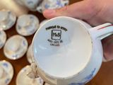 a person holding a cup and saucer on a table