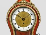une horloge rouge et dorée posée sur une surface blanche
