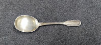 a silver spoon with a spoon handle on a gray surface