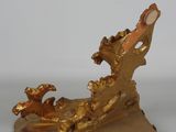 a gold figurine of a bird on a branch