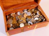 une boîte en bois remplie de pièces de monnaie posée sur une surface blanche