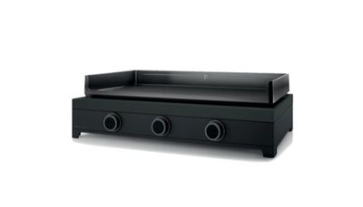 une grille noire surmontée de trois brûleurs