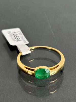 a close up of a ring with a green stone on a table