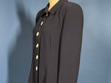 a black jacket on a mannequin stand against a blue wall