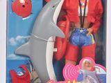 La poupée Barbie porte une veste rouge et un jean bleu.