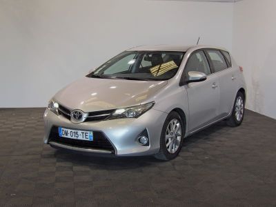 La Toyota Corolla argentée est garée dans une pièce au sol carrelé en damier.