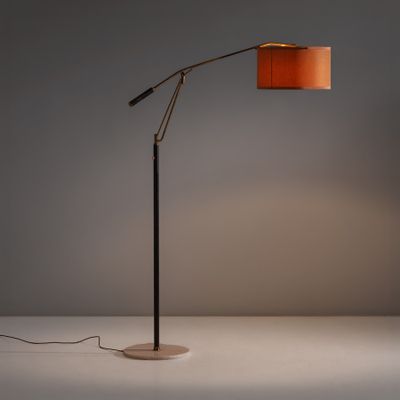 un lampadaire avec un abat-jour orange posé sur une surface blanche