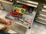 un homme en train d'ouvrir un tiroir contenant des outils