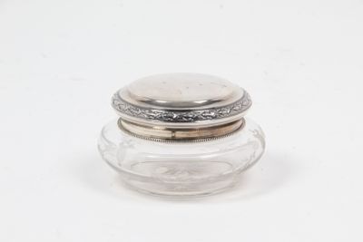 a small glass jar with a silver lid sitting on a white surface