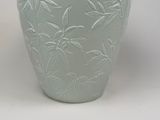 a green vase with a design of bamboo leaves on it