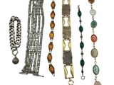 several different bracelets and necklaces are displayed on a white surface