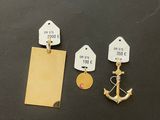 two tags and a gold anchor on a black table