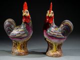 une paire de figurines de coqs en céramique colorées posées sur une table