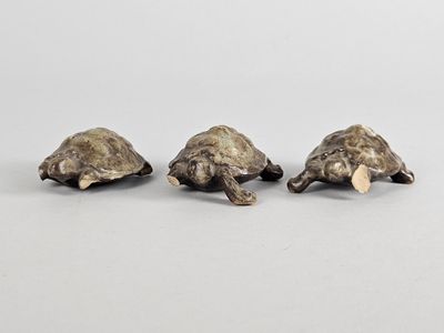 trois figurines de tortues en bronze empilées les unes sur les autres