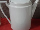 a white tea pot and a glass on a red table
