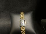 a close up of a watch on a black bag with a gold chain