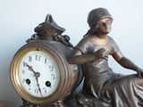 a statue of a woman sitting next to a clock on a table