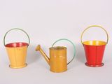 three different colors of watering cans on a white surface
